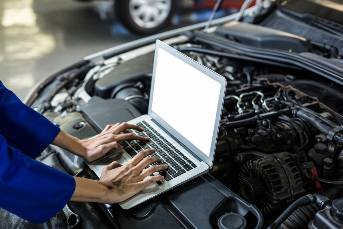 Hands of female mechanic using laptop in repair garage searching for trusted car parts online